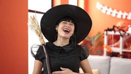 Téléchargez les photos : Young chinese woman wearing witch costume holding broom at home - en image libre de droit