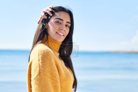 Téléchargez les photos : Jeune femme hispanique souriant confiance debout au bord de la mer - en image libre de droit