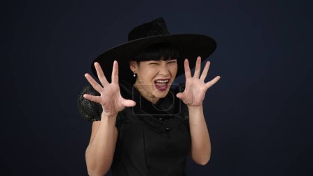 Foto de Joven mujer china con traje de bruja haciendo gesto de miedo sobre fondo negro aislado - Imagen libre de derechos