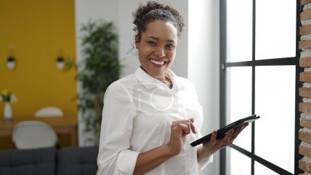 Téléchargez les photos : African american woman smiling confident using touchpad at home - en image libre de droit