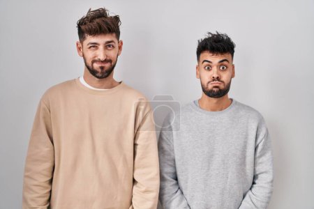 Photo for Young homosexual couple standing over white background puffing cheeks with funny face. mouth inflated with air, crazy expression. - Royalty Free Image