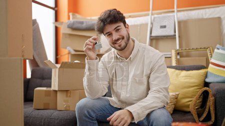Foto de Joven hombre hispano sonriendo confiado sosteniendo nuevas llaves de la casa en nuevo hogar - Imagen libre de derechos
