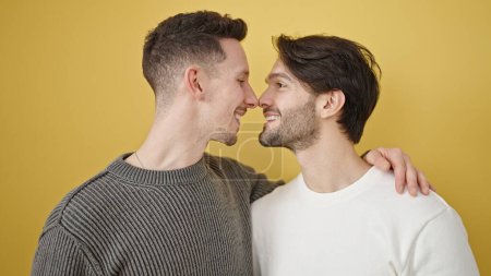 Téléchargez les photos : Deux hommes couple serrant l'un l'autre debout sur fond jaune isolé - en image libre de droit