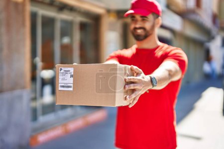 Photo for Young hispanic man courier holding package at street - Royalty Free Image