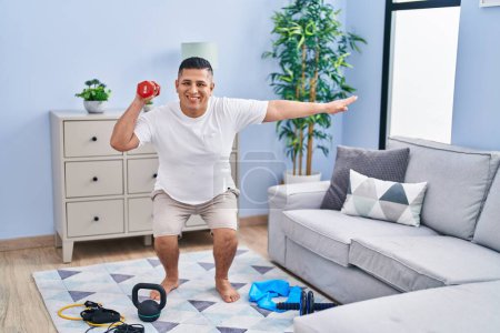 Téléchargez les photos : Jeune latin homme entraînement jambe exercice à l'aide haltère à la maison - en image libre de droit
