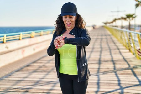 Photo for Middle age hispanic woman working out with smart watch at promenade - Royalty Free Image