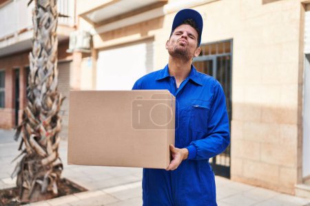 Photo for Young hispanic man delivering box looking at the camera blowing a kiss being lovely and sexy. love expression. - Royalty Free Image
