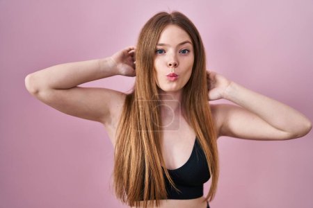 Photo for Young caucasian woman wearing lingerie over pink background making fish face with mouth and squinting eyes, crazy and comical. - Royalty Free Image