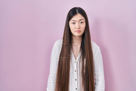 Photo for Chinese young woman standing over pink background looking sleepy and tired, exhausted for fatigue and hangover, lazy eyes in the morning. - Royalty Free Image