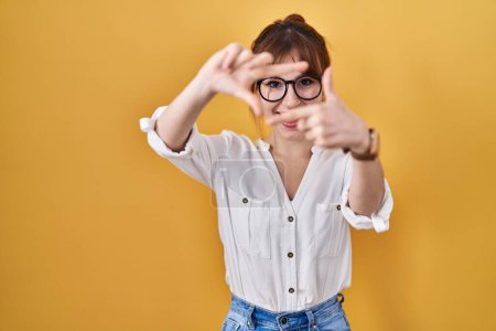 Photo for Young beautiful woman wearing casual shirt over yellow background smiling making frame with hands and fingers with happy face. creativity and photography concept. - Royalty Free Image