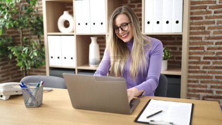 Téléchargez les photos : Jeune femme blonde travailleuse d'affaires utilisant un ordinateur portable travaillant au bureau - en image libre de droit