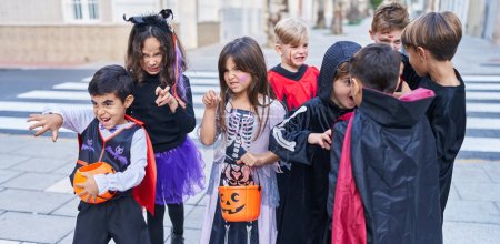 Foto de Grupo de niños con disfraz de Halloween haciendo gesto de miedo en la calle - Imagen libre de derechos