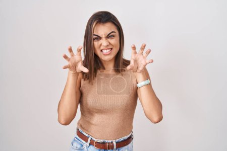 Photo for Young hispanic woman standing over white background smiling funny doing claw gesture as cat, aggressive and sexy expression - Royalty Free Image