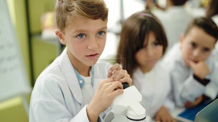 Foto de Grupo de niños estudiantes que usan microscopio en el aula de laboratorio - Imagen libre de derechos