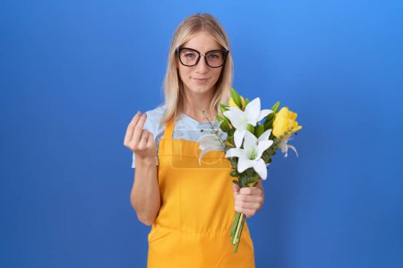 Photo for Young caucasian woman wearing florist apron holding flowers doing money gesture with hands, asking for salary payment, millionaire business - Royalty Free Image