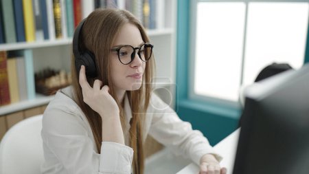 Téléchargez les photos : Young blonde woman student using computer studying at university classroom - en image libre de droit