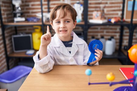 Photo for Little caucasian boy at school scientist laboratory winning first prize smiling with an idea or question pointing finger with happy face, number one - Royalty Free Image
