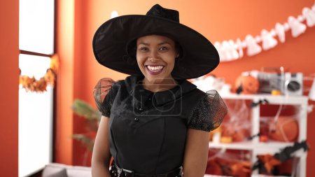 Téléchargez les photos : Femme afro-américaine portant costume de sorcière ayant fête d'Halloween à la maison - en image libre de droit