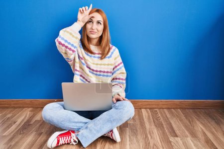 Photo for Young woman using laptop at home sitting on the floor making fun of people with fingers on forehead doing loser gesture mocking and insulting. - Royalty Free Image