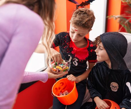 Foto de Grupo de chicos con disfraz de Halloween recibiendo caramelos en casa - Imagen libre de derechos