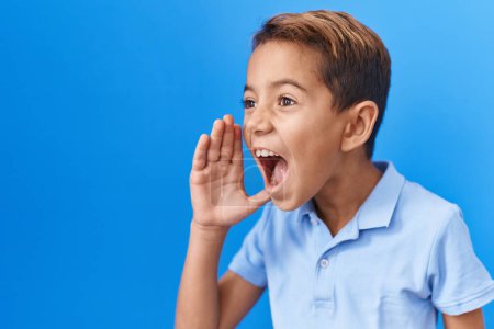 Foto de Pequeño niño hispano con camiseta azul casual despistado y confundido con los brazos abiertos, ni idea y cara dudosa. - Imagen libre de derechos