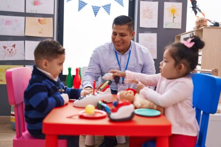 Photo for Hispanic man with boy and girl playing supermarket game sitting on table at kindergarten - Royalty Free Image
