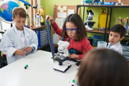 Foto de Grupo de estudiantes de niños que utilizan un dispositivo de reparación de microscopio en el aula de laboratorio - Imagen libre de derechos