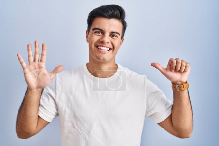 Photo for Hispanic man standing over blue background showing and pointing up with fingers number six while smiling confident and happy. - Royalty Free Image
