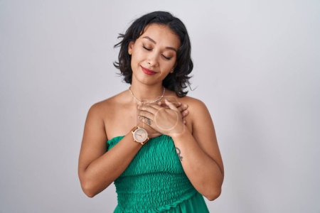 Photo for Young hispanic woman standing over isolated background smiling with hands on chest with closed eyes and grateful gesture on face. health concept. - Royalty Free Image