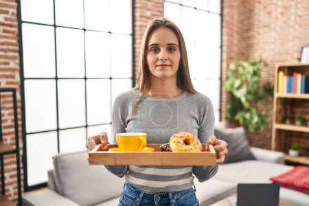 Photo for Young woman holding tray with breakfast food relaxed with serious expression on face. simple and natural looking at the camera. - Royalty Free Image