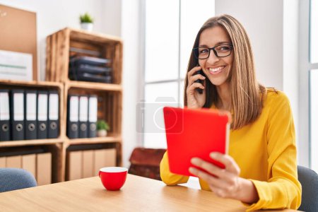 Téléchargez les photos : Young woman business worker talking on the smartphone using touchpad at office - en image libre de droit