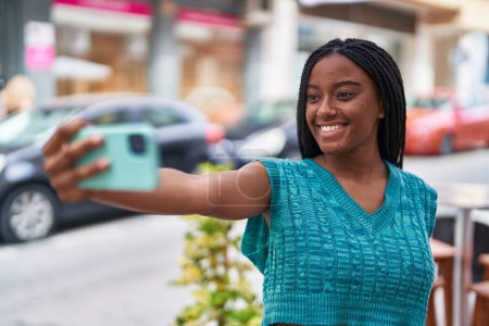 Foto de Mujer afroamericana sonriendo confiada haciendo selfie por el teléfono inteligente en la calle - Imagen libre de derechos