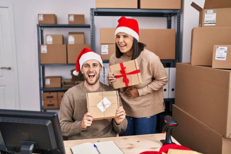Foto de Dos jóvenes que trabajan en el comercio electrónico de pequeñas empresas en Navidad sonriendo y riendo en voz alta porque divertido chiste loco. - Imagen libre de derechos
