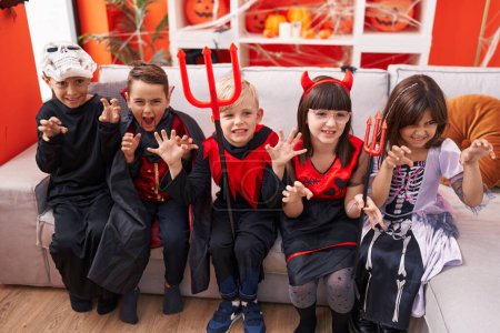Téléchargez les photos : Groupe d'enfants portant un costume d'Halloween faisant geste effrayant à la maison - en image libre de droit