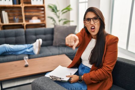 Photo for Young hispanic woman working as psychology counselor pointing displeased and frustrated to the camera, angry and furious with you - Royalty Free Image