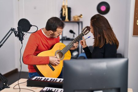 Téléchargez les photos : Musiciens d'âge moyen ayant des cours de guitare au studio de musique - en image libre de droit