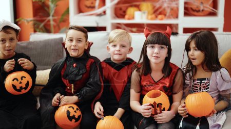 Foto de Grupo de niños con disfraz de halloween sosteniendo cesta de calabaza en casa - Imagen libre de derechos