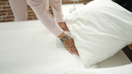 Photo for Middle age hispanic woman make bed at bedroom - Royalty Free Image