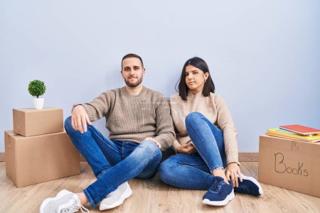 Photo for Young couple moving to a new home relaxed with serious expression on face. simple and natural looking at the camera. - Royalty Free Image