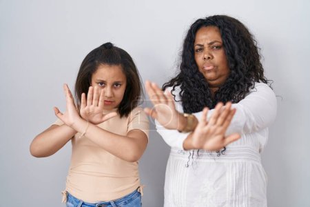 Photo for Mother and young daughter standing over white background rejection expression crossing arms and palms doing negative sign, angry face - Royalty Free Image