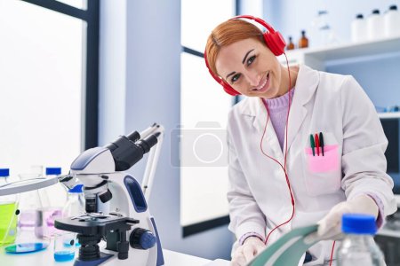 Téléchargez les photos : Young caucasian woman scientist listening to music reading notebook at laboratory - en image libre de droit