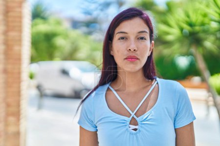Téléchargez les photos : Jeune belle femme hispanique avec une expression détendue debout dans la rue - en image libre de droit