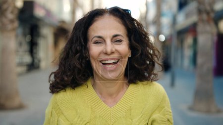 Téléchargez les photos : Moyen âge hispanique femme souriant confiant à la rue - en image libre de droit