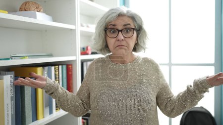 Téléchargez les photos : Femme d'âge moyen avec professeur de cheveux gris debout avec je ne sais quelle expression à l'université - en image libre de droit