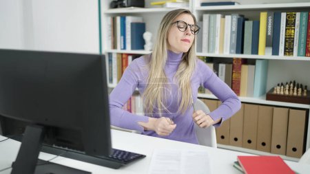 Téléchargez les photos : Jeune étudiante blonde utilisant un ordinateur jouant du tambour à la bibliothèque de l'université - en image libre de droit
