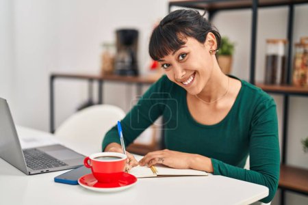 Photo for Young beautiful hispanic woman sitting on table studying at home - Royalty Free Image