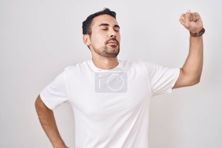 Photo for Handsome hispanic man standing over white background stretching back, tired and relaxed, sleepy and yawning for early morning - Royalty Free Image
