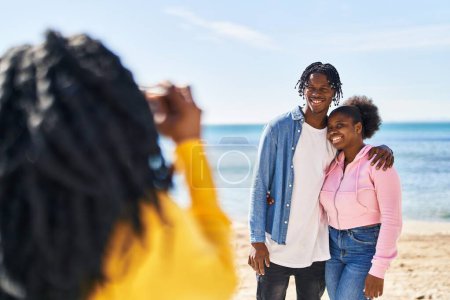 Foto de Amigos afroamericanos abrazándose haciendo fotos en la playa - Imagen libre de derechos