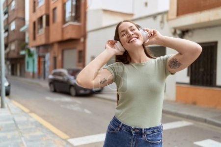 Photo for Young beautiful woman listening to music and dancing at street - Royalty Free Image
