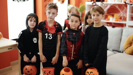 Téléchargez les photos : Groupe d'enfants portant costume d'Halloween tenant panier de citrouille à la maison - en image libre de droit